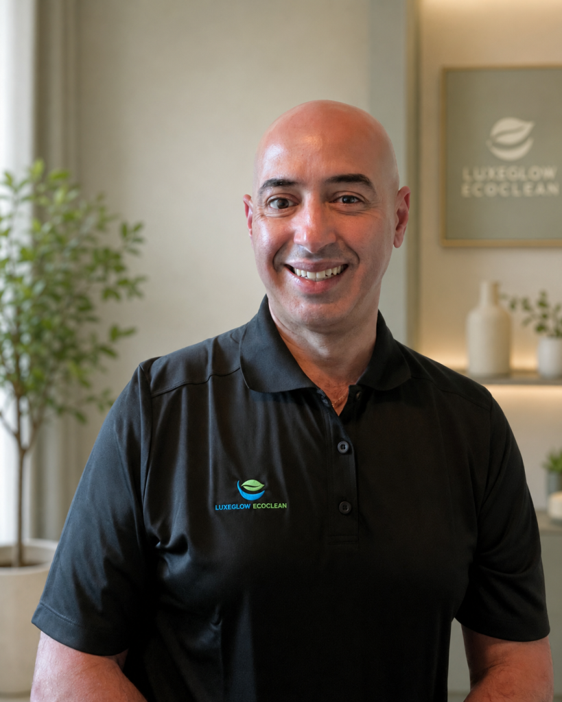 Mounir, founder of LuxeGlow EcoClean, wearing a branded black polo in a warm professional home setting.